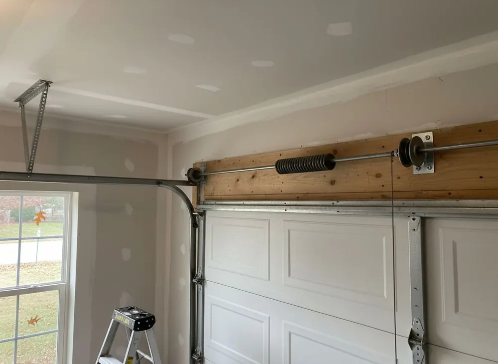 Torsion spring and cable drum on a steel shaft above a garage door